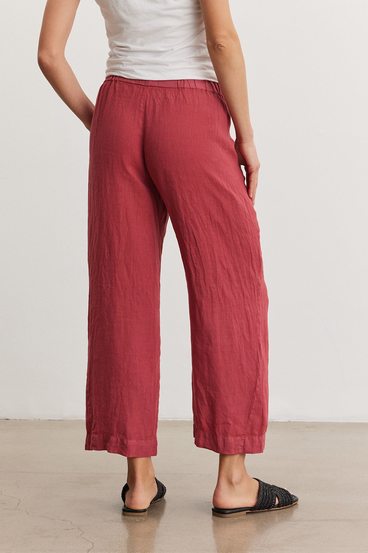 A person wearing the Velvet by Graham & Spencer LOLA LINEN PANT and black woven flats, standing with a side view against a neutral background.-36909573374145