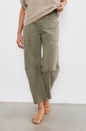 A person wearing Velvet by Graham & Spencer's BRYLIE SANDED TWILL UTILITY PANT with patch pockets and tan slide sandals, standing against a plain white background.