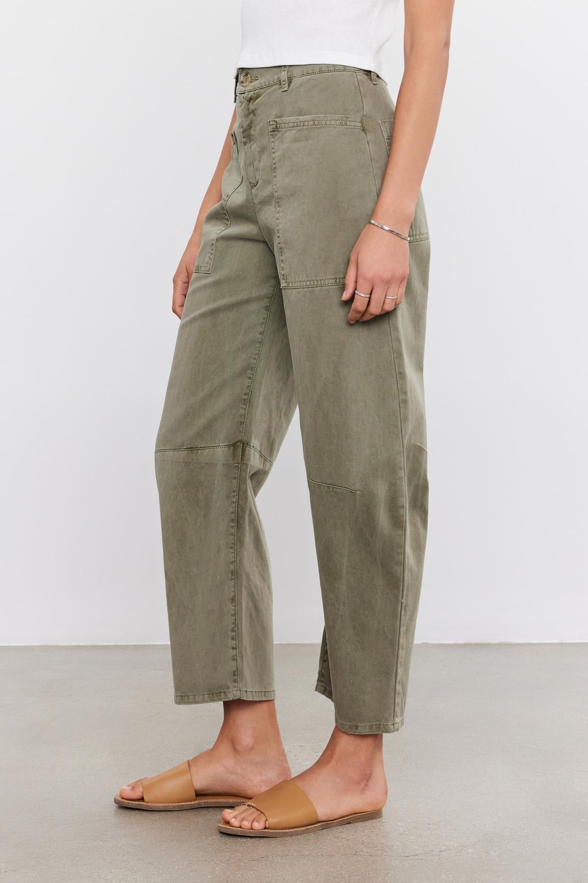 Woman standing in a side profile view wearing Velvet by Graham & Spencer BRYLIE SANDED TWILL UTILITY PANT trousers and tan slide sandals on a white background.-37000518107329