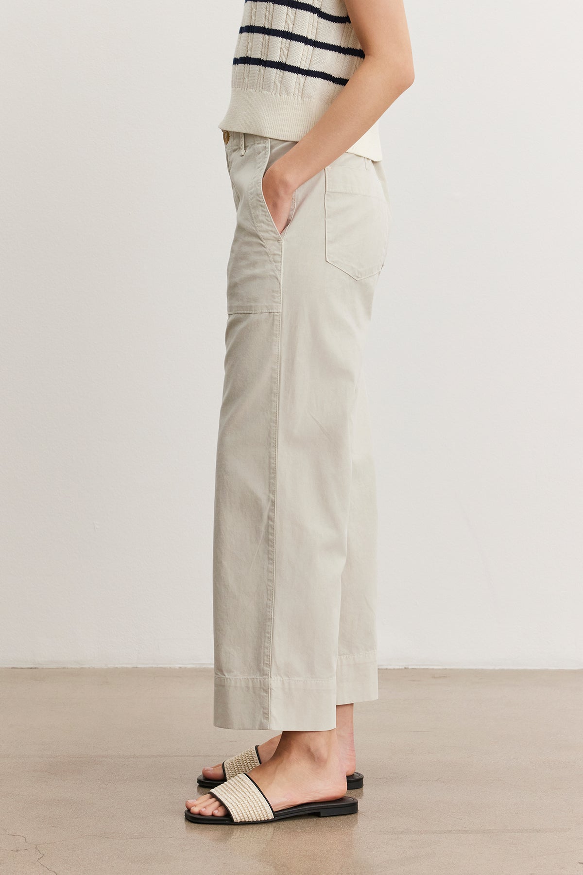 A woman standing in a neutral pose wearing a striped tank top, light gray Velvet by Graham & Spencer MYA COTTON CANVAS PANTS, and black slide sandals. Only the lower half of her body is visible.-36998760759489