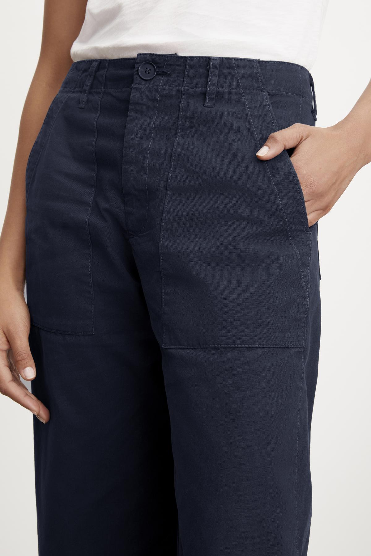 Close-up of a woman's hand touching the pocket of MYA COTTON CANVAS PANTS by Velvet by Graham & Spencer, highlighting the stitching and fabric texture.-36999933984961