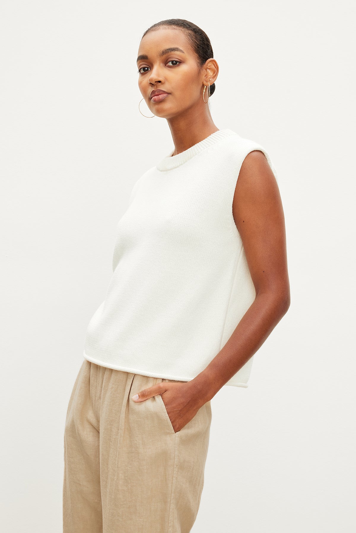   The model is wearing a white ASTER CREW NECK SWEATER and tan trousers, made of a luxurious cotton cashmere blend by Velvet by Graham & Spencer. 