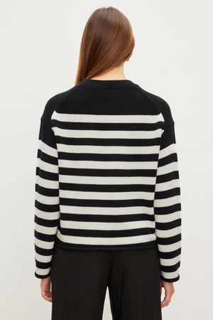 The modern silhouette of a woman wearing a Velvet by Graham & Spencer LEX STRIPED CREW NECK SWEATER.