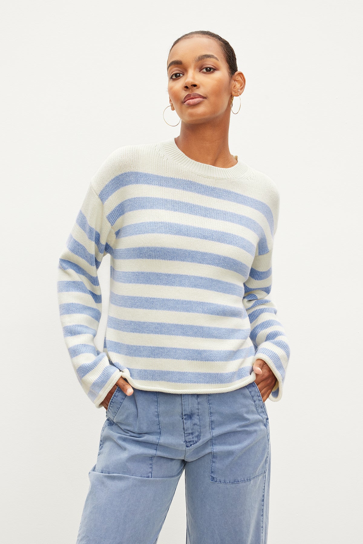 The modern model is wearing a blue and white striped LEX STRIPED CREW NECK SWEATER by Velvet by Graham & Spencer.-35967621660865