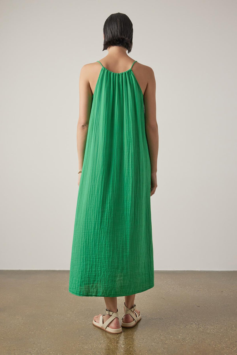 Woman standing with her back to the camera, wearing a green sleeveless CARRILLO DRESS by Velvet by Jenny Graham and white sandals, against a neutral background.