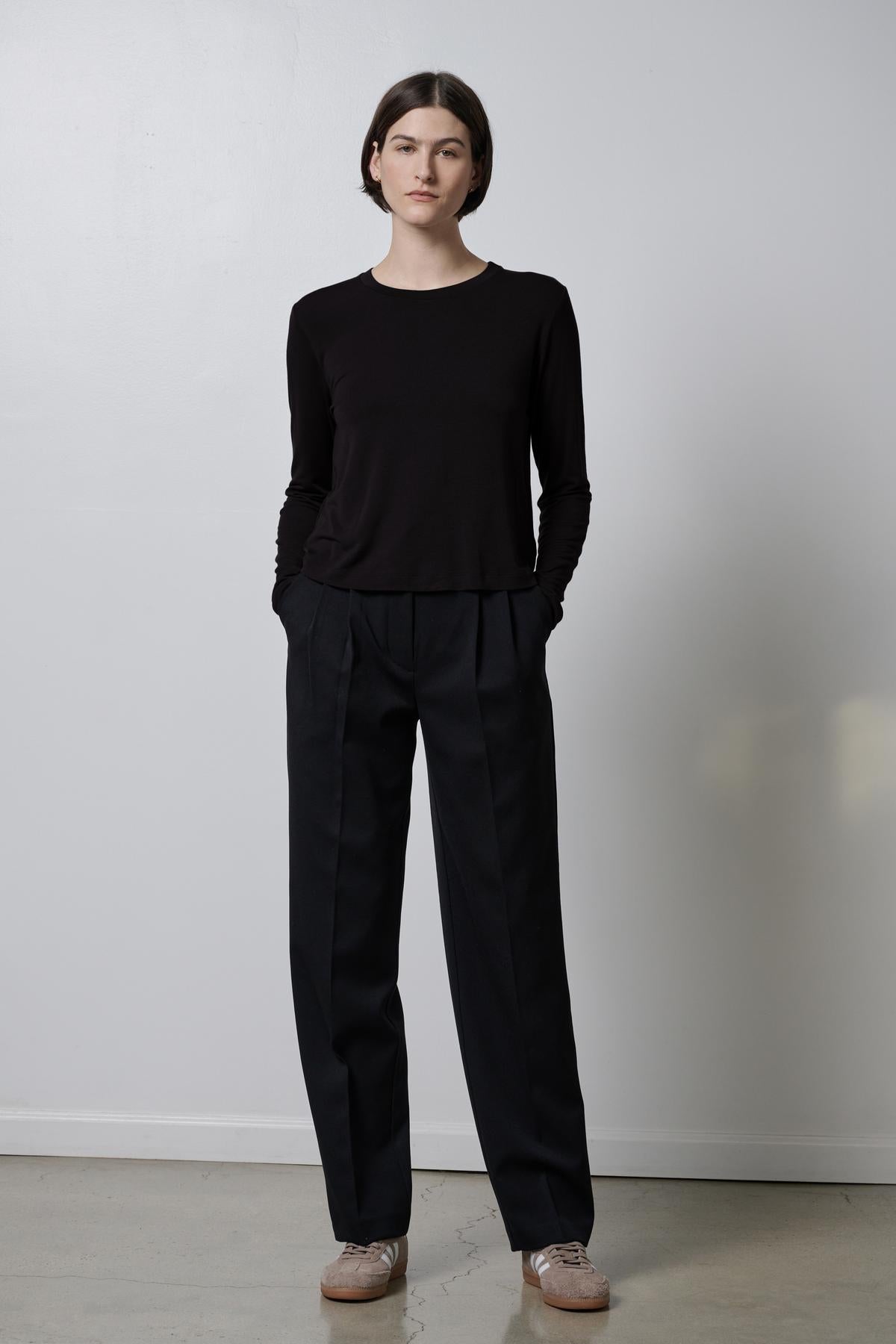 A woman wearing black rib knit trousers and a soft hand black Velvet by Jenny Graham sweater.-35495907688641