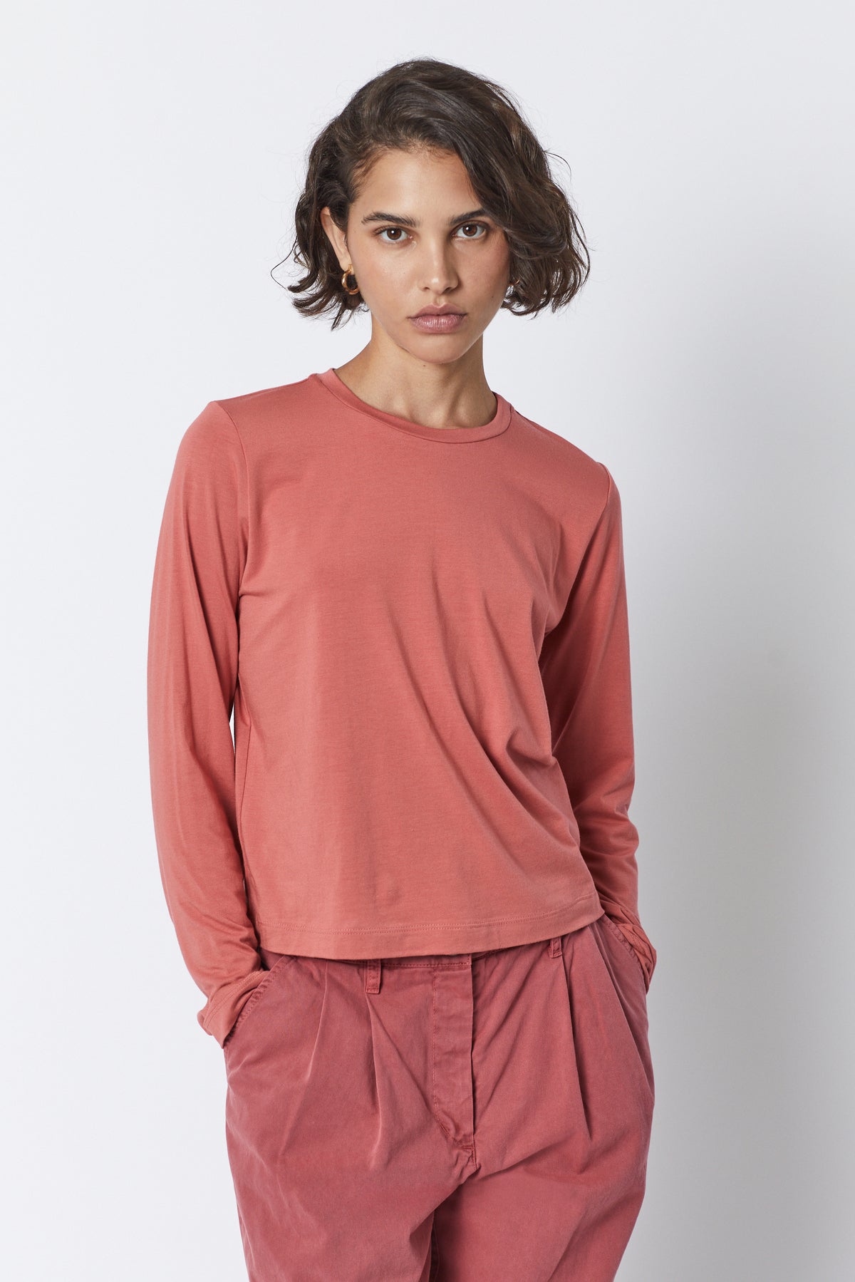 The model is wearing a Velvet by Jenny Graham pink long-sleeved PACIFICA TEE with a soft hand and pleated pants.-35495909523649