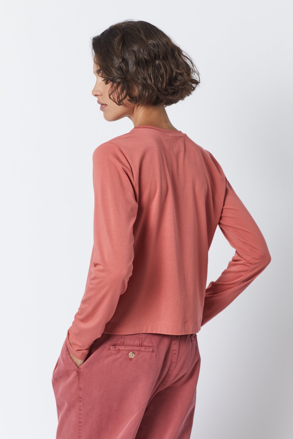 The back view of a woman wearing pink pants and a long-sleeved Velvet by Jenny Graham PACIFICA TEE made from rib knit fabric.-35495909621953