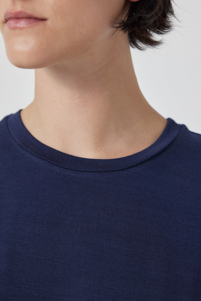 Close-up of a person wearing a blue Velvet by Jenny Graham Solana Tee, partial view of the face showing a smile.