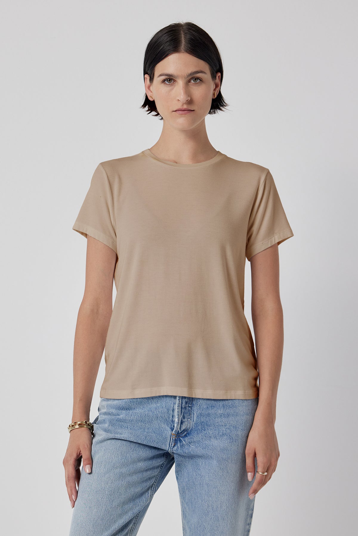 Woman modeling a classic Solana Tee by Velvet by Jenny Graham in beige and blue jeans against a white background.-36290532344001