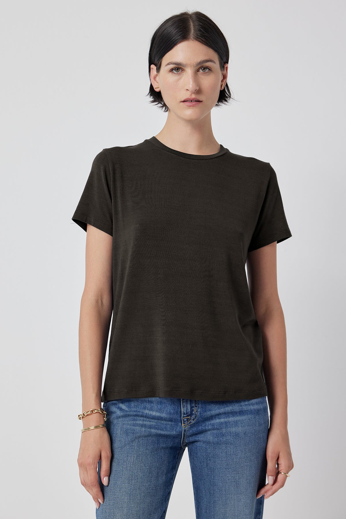 A woman in a Solana Tee by Velvet by Jenny Graham and blue jeans standing against a white background.-36290523529409