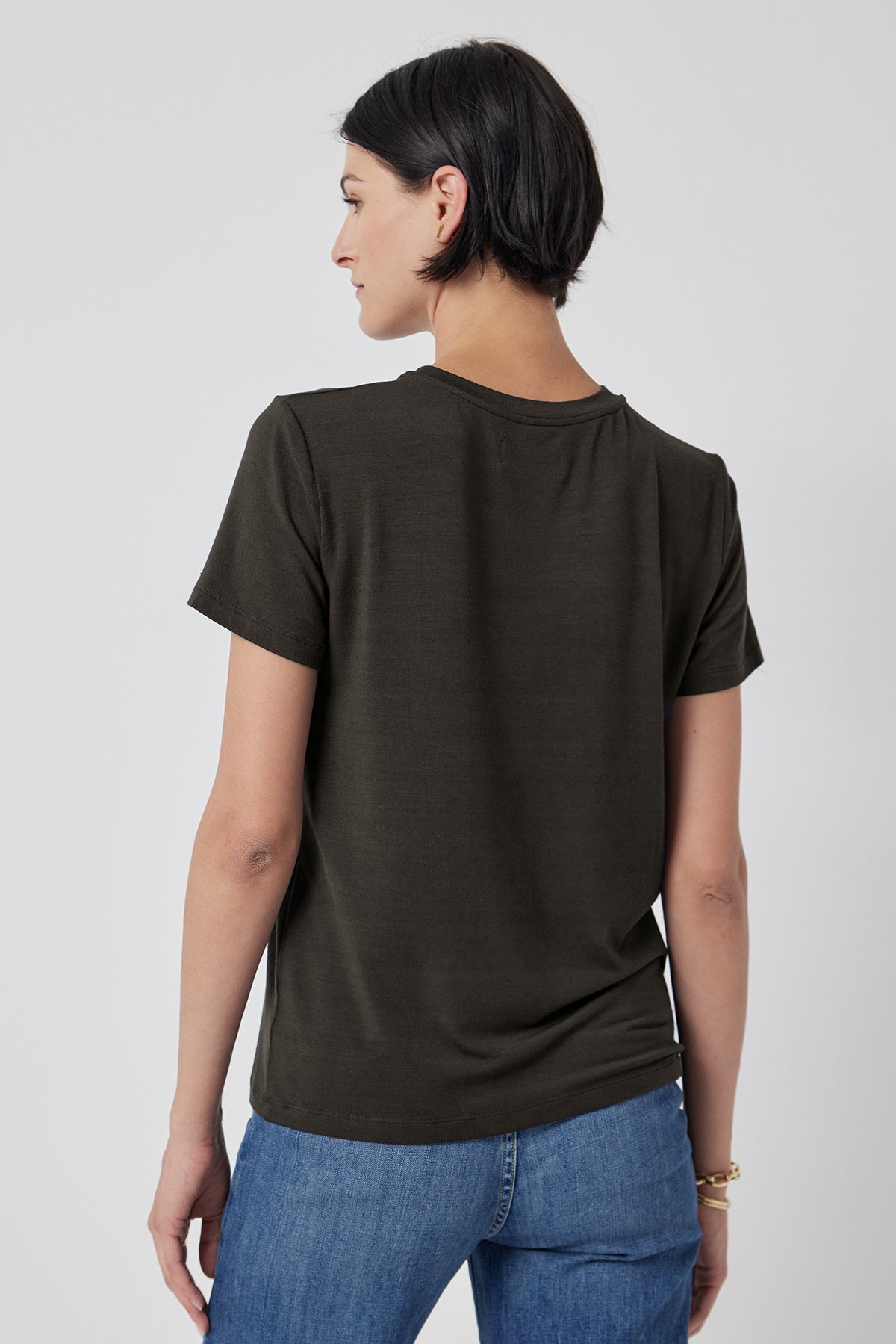 Woman wearing a plain SOLANA TEE in olive green from Velvet by Jenny Graham and blue jeans viewed from the back.-36290523562177