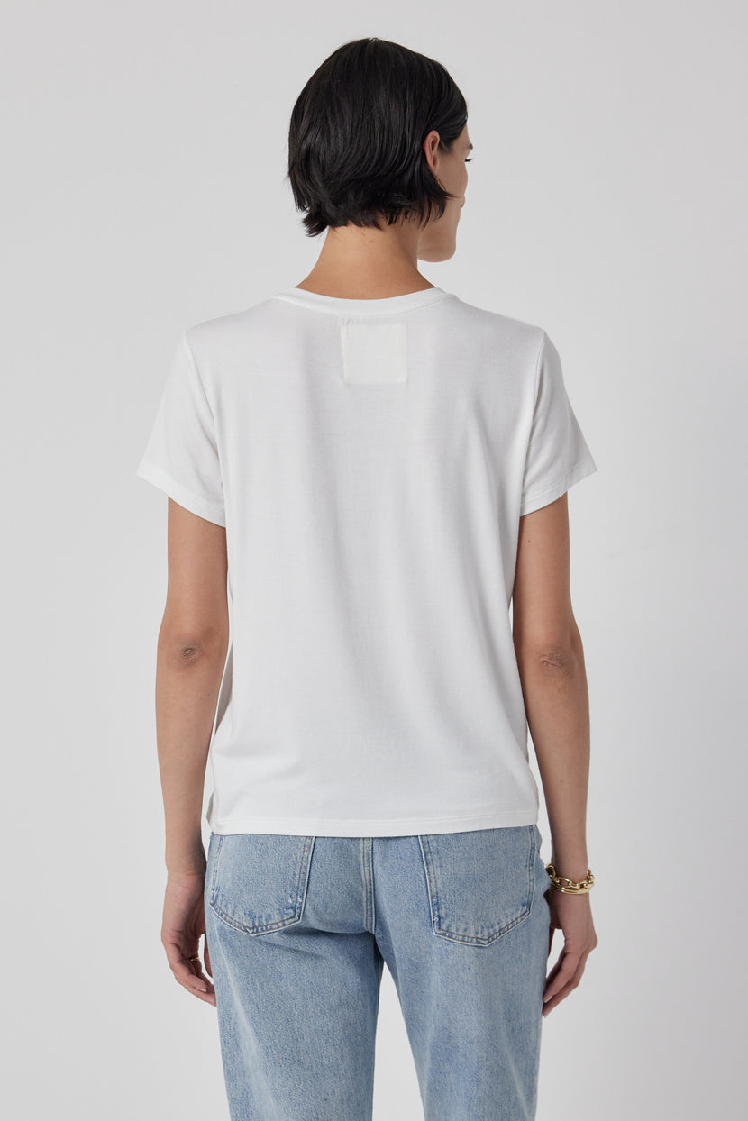 The woman is wearing a white Velvet by Jenny Graham SOLANA TEE and jeans, showing off the shrunken sleeve.