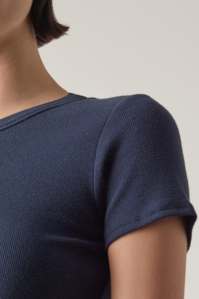 Close-up of a woman wearing a dark blue textured BEDFORD TEE by Velvet by Jenny Graham, with a crew neckline, focusing on the shoulder and neckline details.