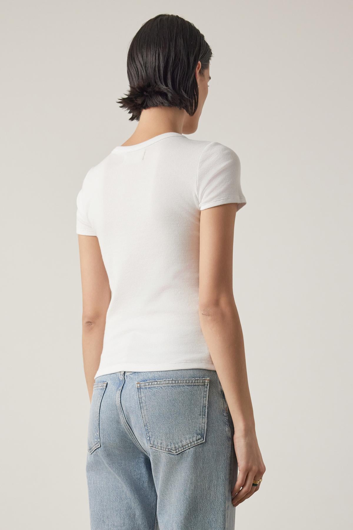 Rear view of a woman in a white BEDFORD TEE from Velvet by Jenny Graham with a crew neckline and blue jeans, focusing on the fit of the clothes.-36753616830657