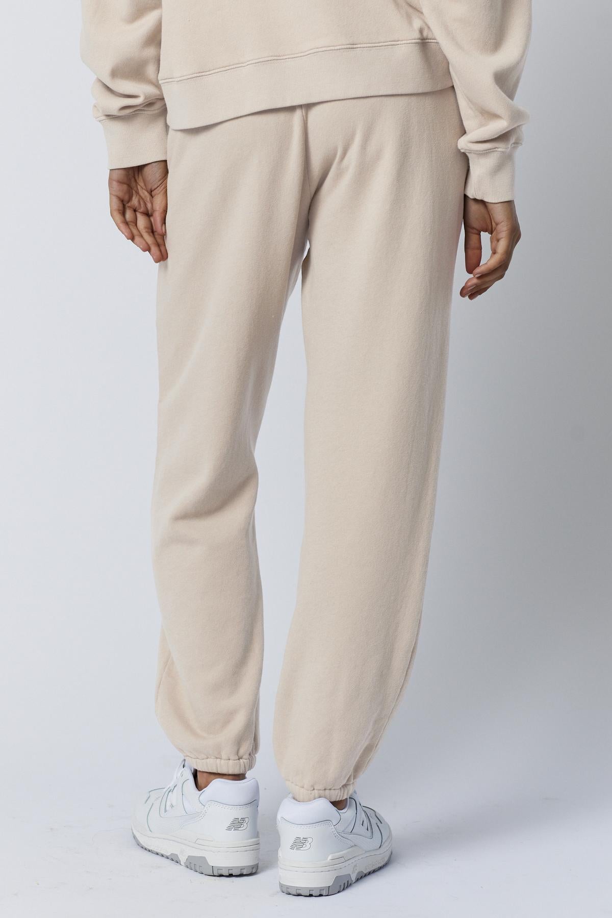 Person wearing ZUMA SWEATPANT by Velvet by Jenny Graham and a matching sweatshirt with white sneakers, standing against a plain background, focus on lower half.-36863305351361
