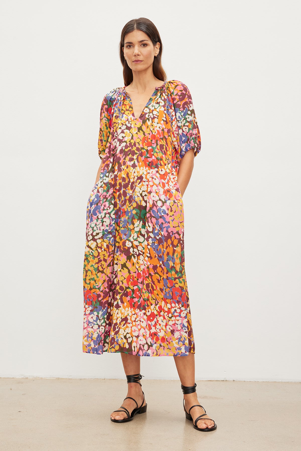 Woman standing in a gallery, wearing a CAROL PRINTED BOHO DRESS by Velvet by Graham & Spencer and black sandals, looking directly at the camera.-35955494158529