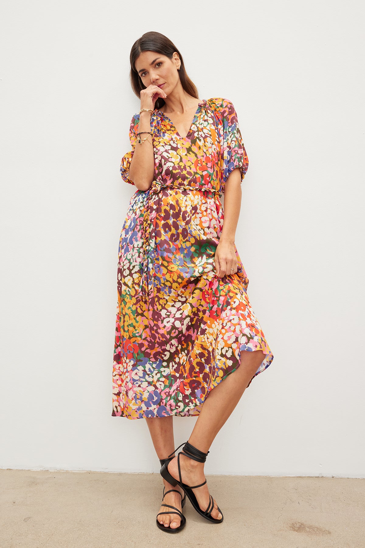 Woman in a CAROL PRINTED BOHO DRESS by Velvet by Graham & Spencer and black sandals, standing against a white background, gently touching her face while looking at the camera.-36691400523969