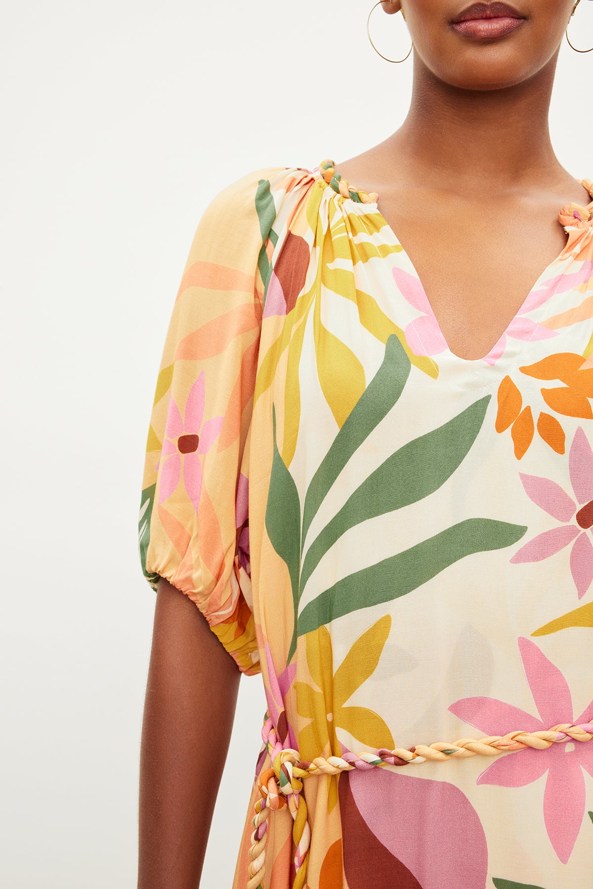 Close-up of a woman wearing a Velvet by Graham & Spencer CAROL PRINTED BOHO DRESS with pink, orange, and green patterns, focusing on the sleeve and neckline details.-35955494387905