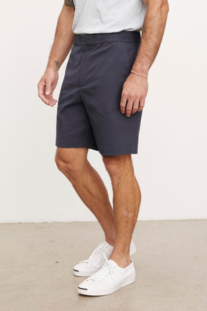 Man standing in a plain background wearing a gray pair of Velvet by Graham & Spencer DAMIAN shorts and white sneakers, showing from waist to shoes.