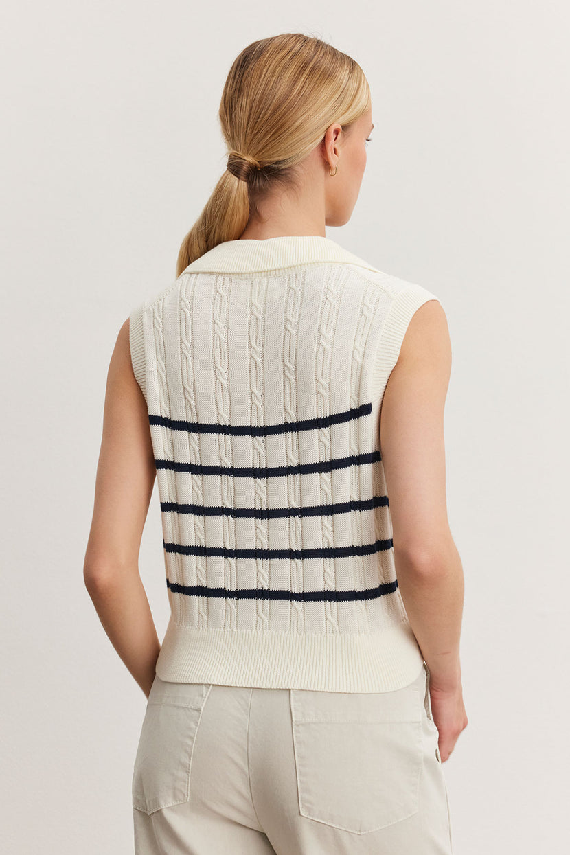 Woman viewed from behind, wearing a white Velvet by Graham & Spencer WENDY SWEATER VEST with horizontal black stripes, paired with beige pants.
