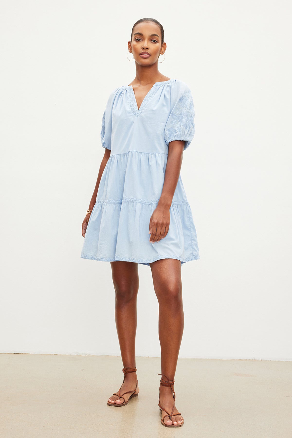 A woman in a light blue CHRISSY EMBROIDERED BOHO DRESS from Velvet by Graham & Spencer with floral embroidery and tan sandals stands confidently against a plain white background.-35955557269697