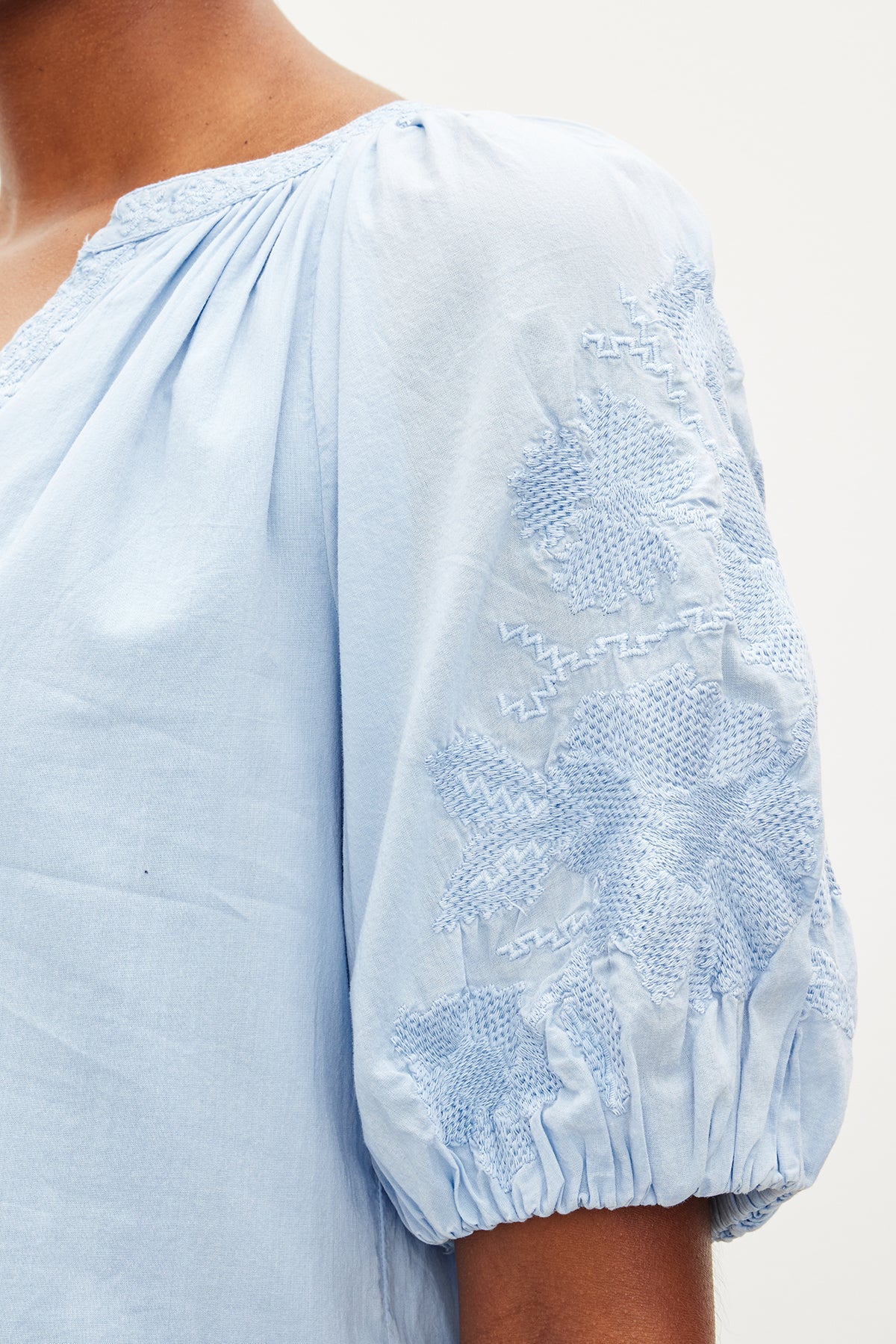 Close-up of a person wearing a Velvet by Graham & Spencer CHRISSY EMBROIDERED BOHO DRESS with delicate floral embroidery on the shoulder.-35955557433537