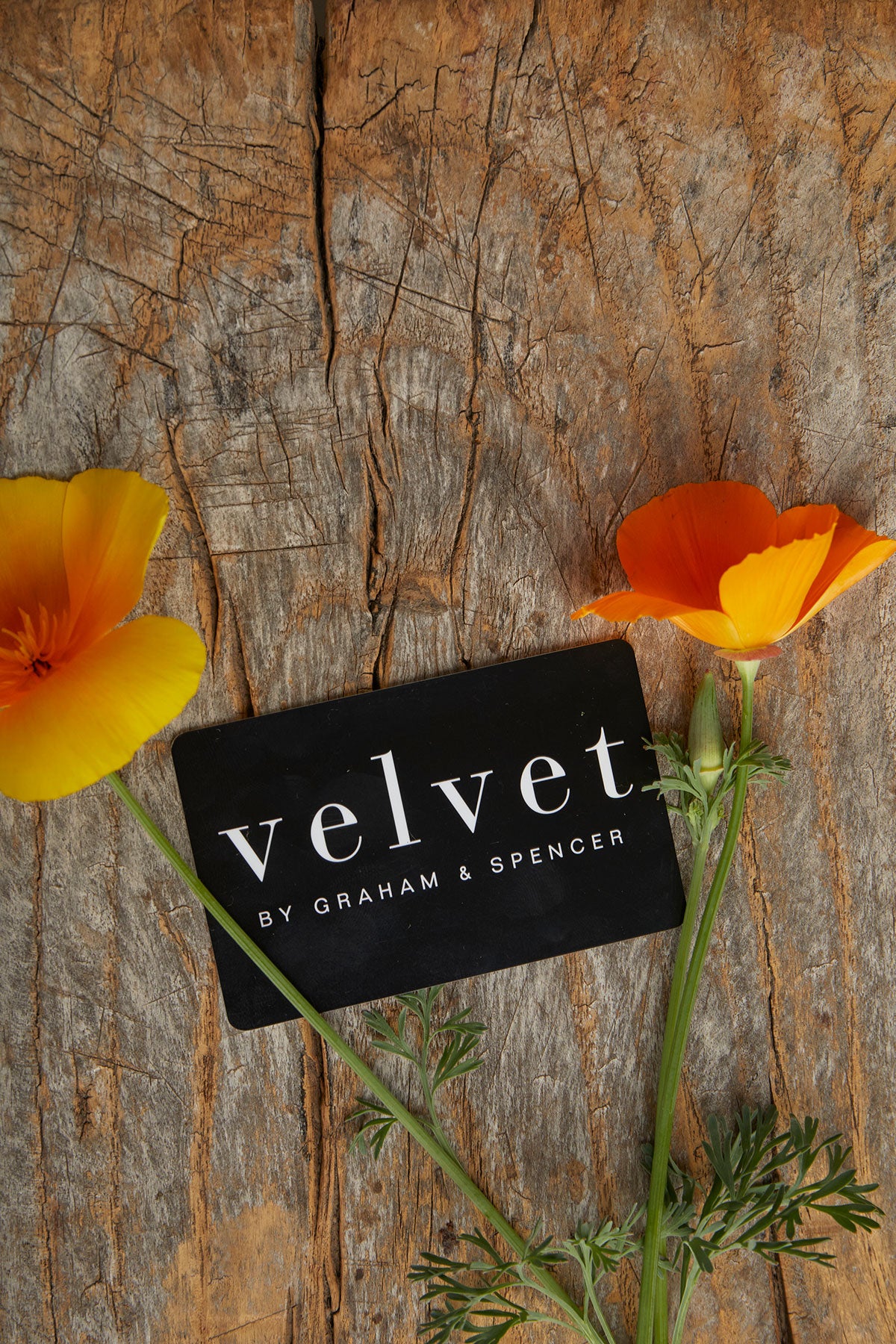A Velvet by Graham & Spencer E-Gift Card sitting on a wooden table.-26296263704769