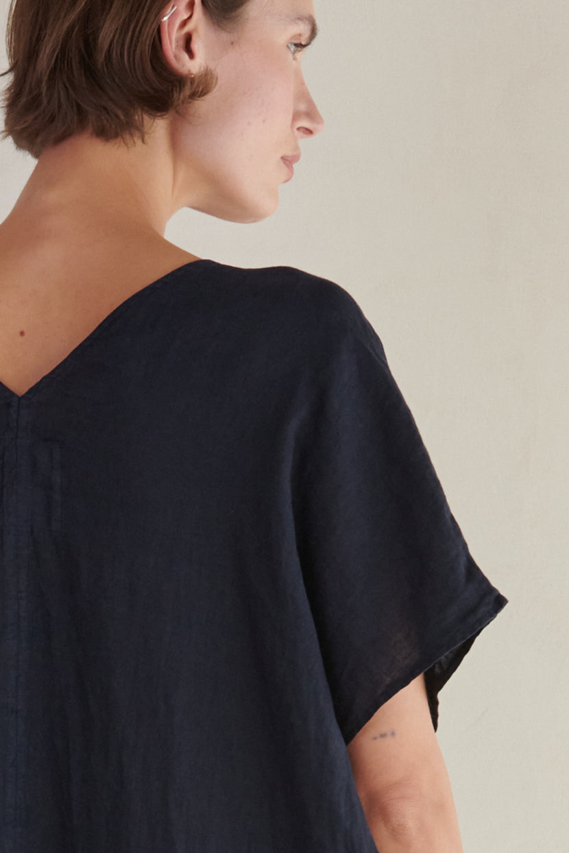 Profile view of a woman in a dark blouse with a V neckline, focusing on the neckline and sleeve details of the Velvet by Jenny Graham MONTANA LINEN DRESS.